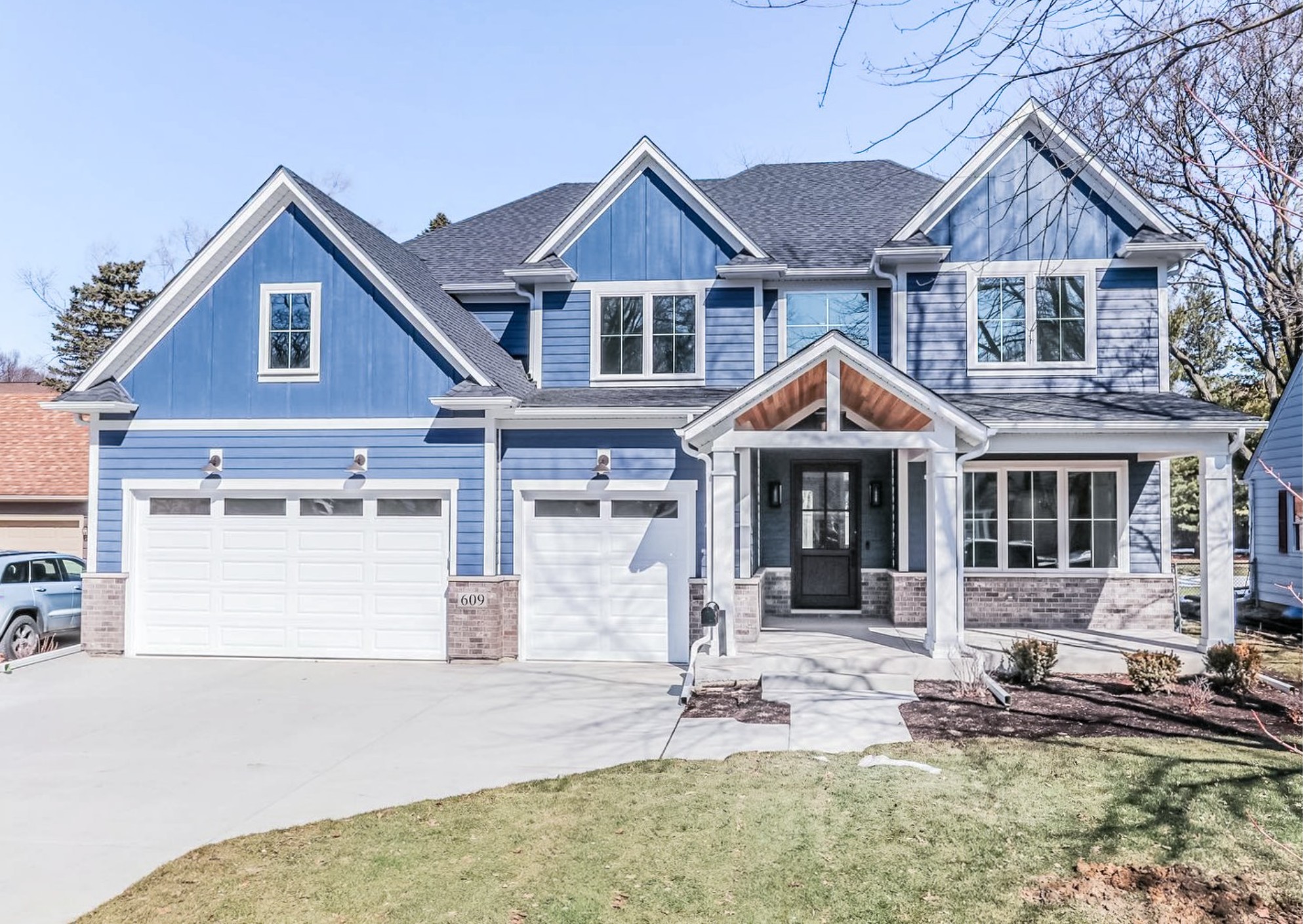 Blue Cape Cod home with matching garage doors