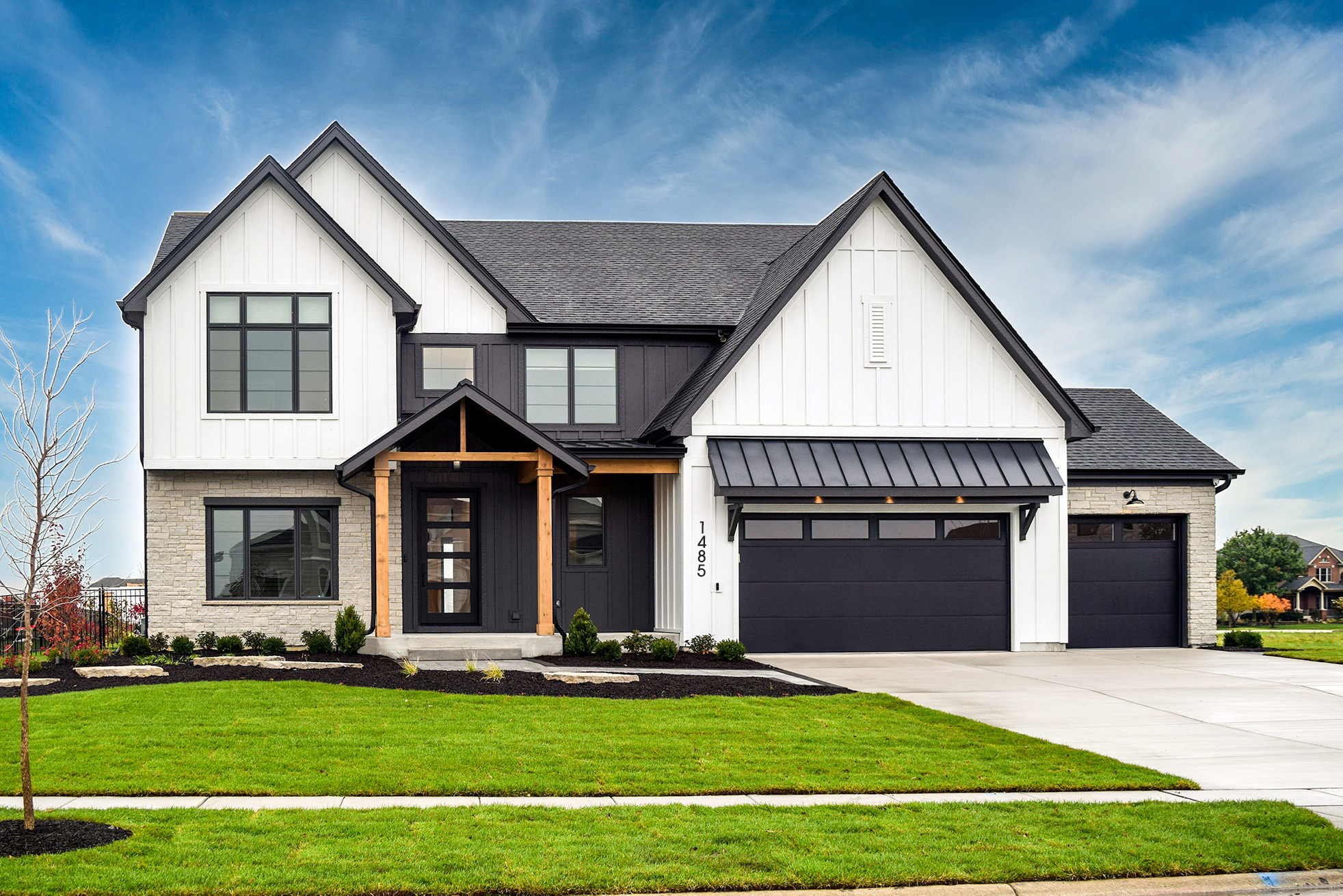 Modern farmhouse home with dark garage doors