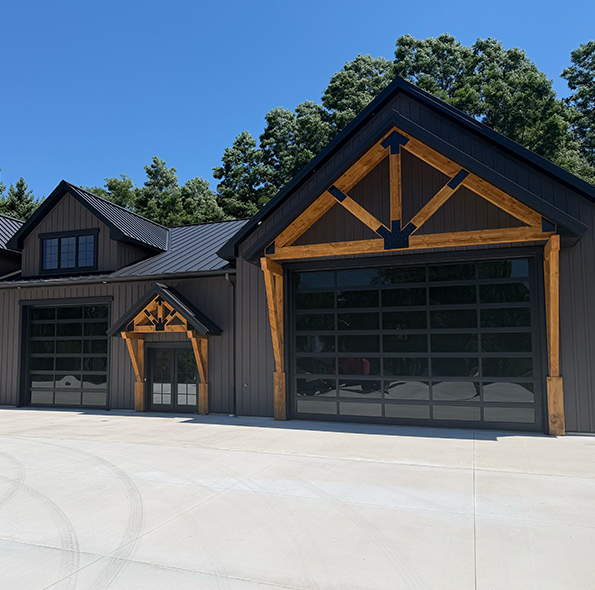 Two white carriage-style sectional garage doors on a modern gray residential home.